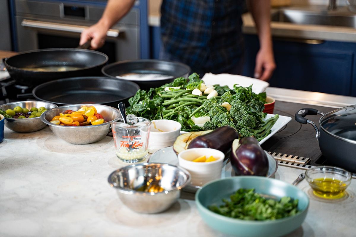 Fresh vegetables, greens, and bowls of ingredients on a home kitchen counter